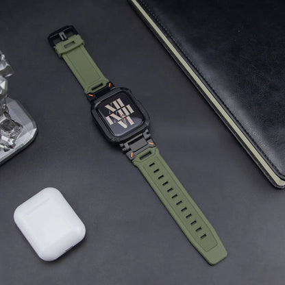 army green apple watch band and black case, laid down on a black table next to air pods and a black notebook