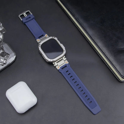 navy blue apple watch band and grey case, laid down on a black table next to air pods and a black notebook